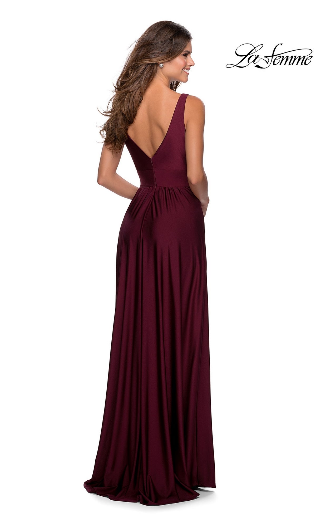 Woman wearing a sleeveless, floor-length burgundy La Femme Deep V-Neck Long A-Line Prom Dress 28547, standing and looking to the side.